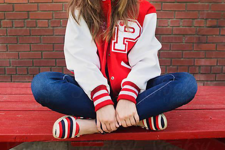 A lady wearing a red varsity bomber jacket with denim