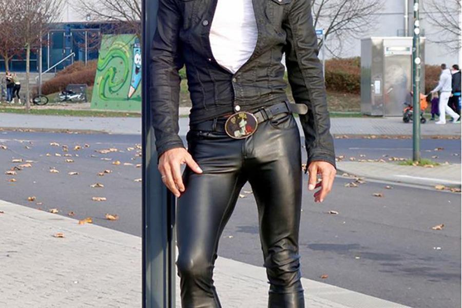 A man wearing black leather pants on a sidewalk