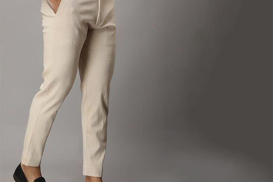 A man wearing cream-colored tapered trousers