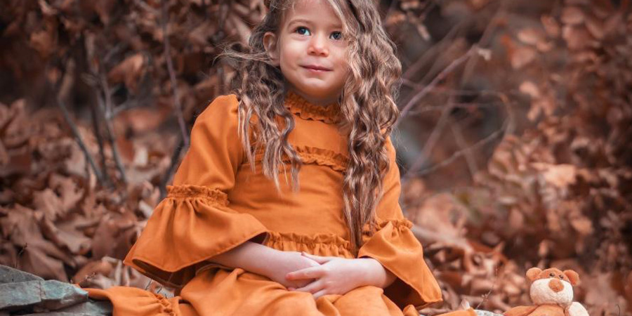 A young girl in an orange dressed-up top