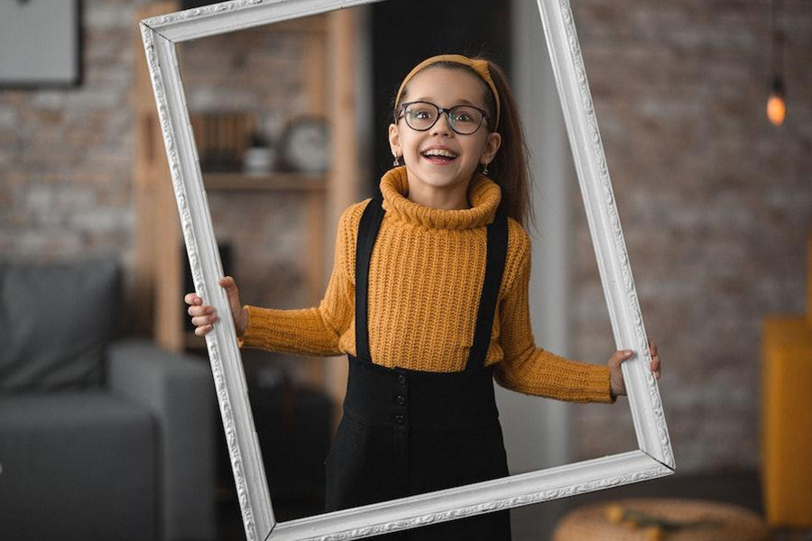A young girl in glasses rocking a light brown sweater