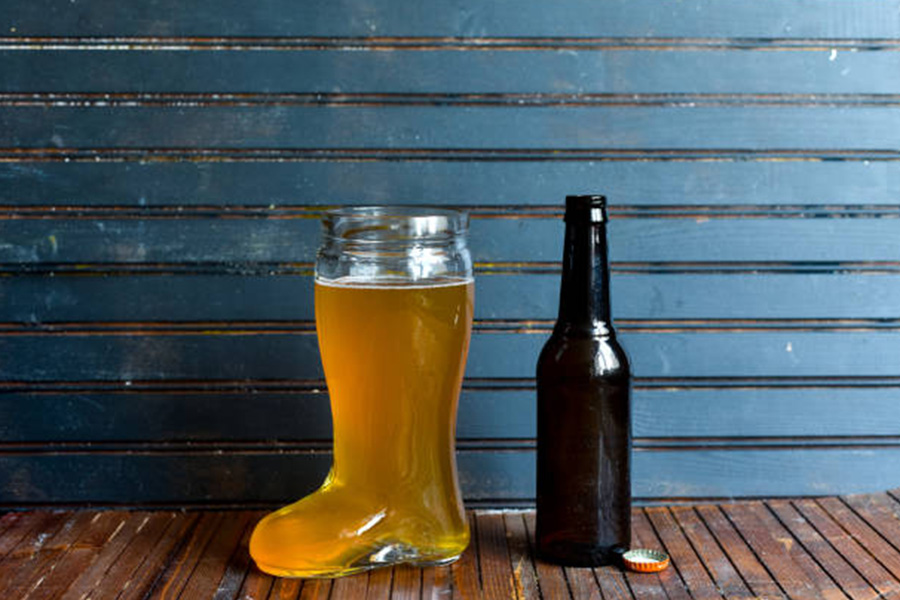 Beer glass in a boot shape next to a bottle
