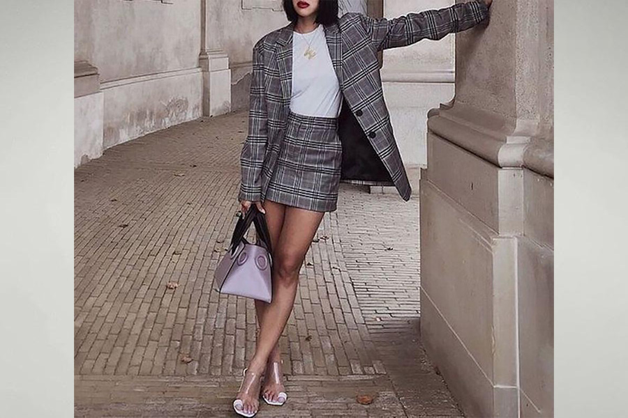 A lady wearing an oversized suit jacket and matching skirt