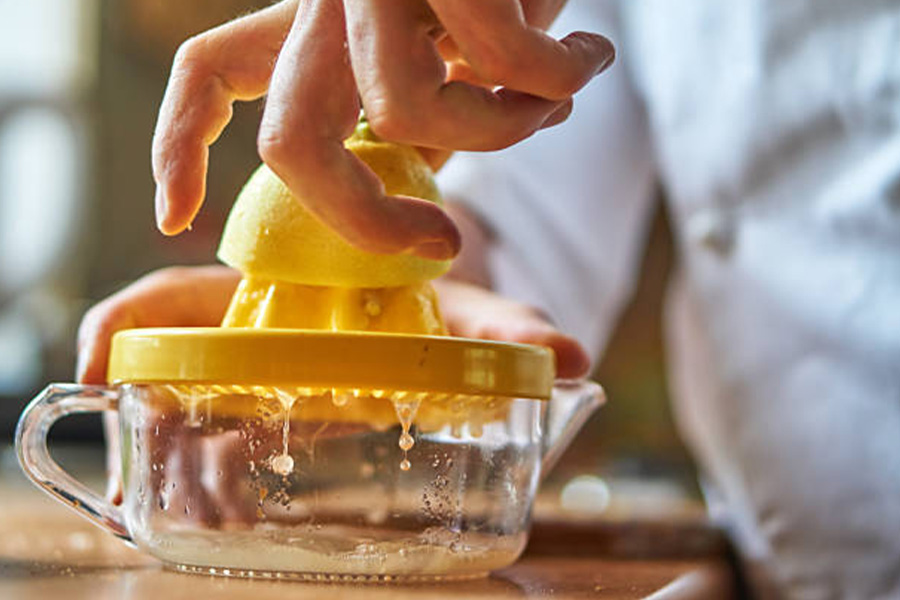Manual citrus juicer being used with a lemon