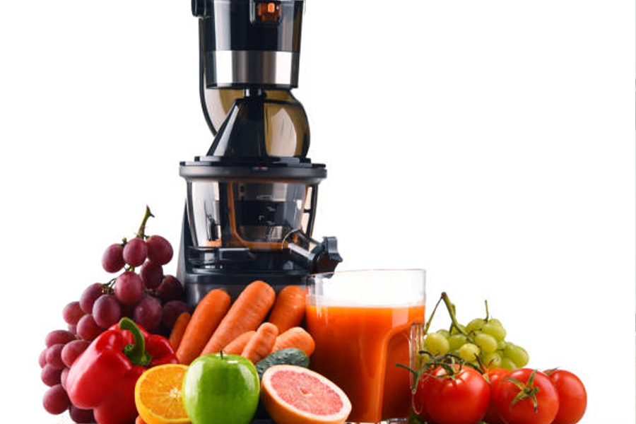 Masticating juicer with fruits and vegetables in front of it