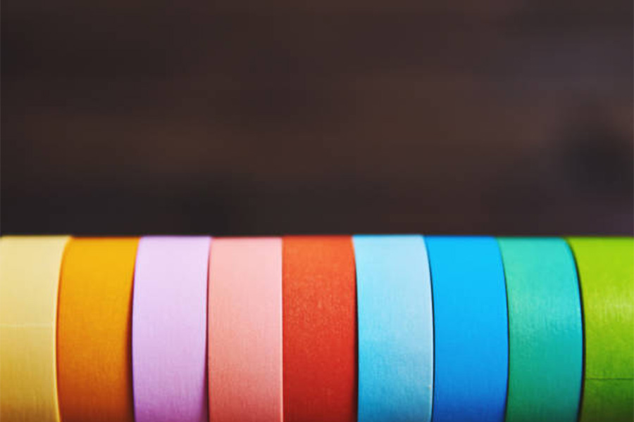 Row of different colors of washi tape against dark backdrop