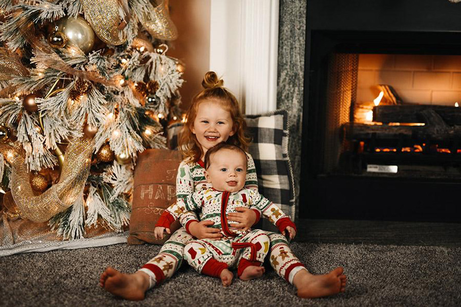Two kids rocking a cozy set of pajamas near fireplace