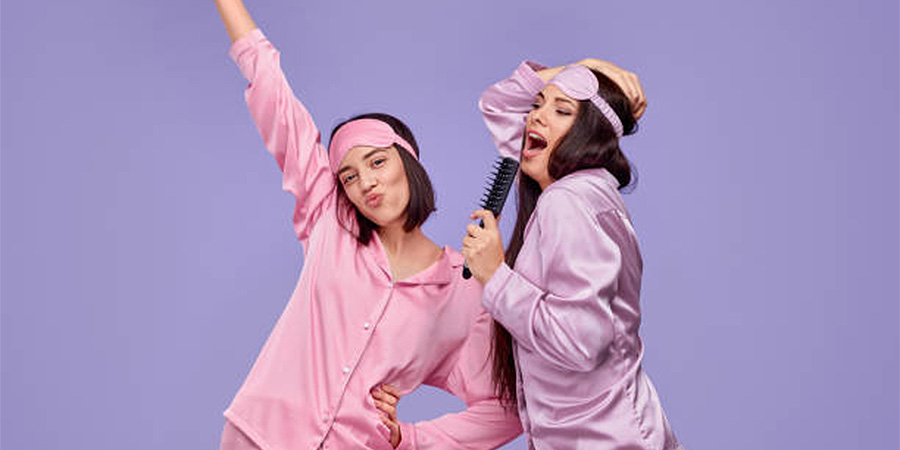 Two women in pink and purple silk pajama sets