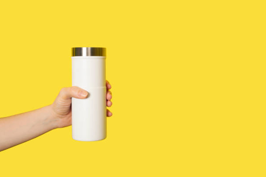 A white travel tumbler against a yellow background