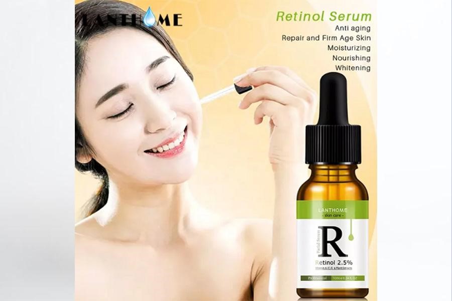 Woman applying retinol skincare serum on her face with the product bottle beside her