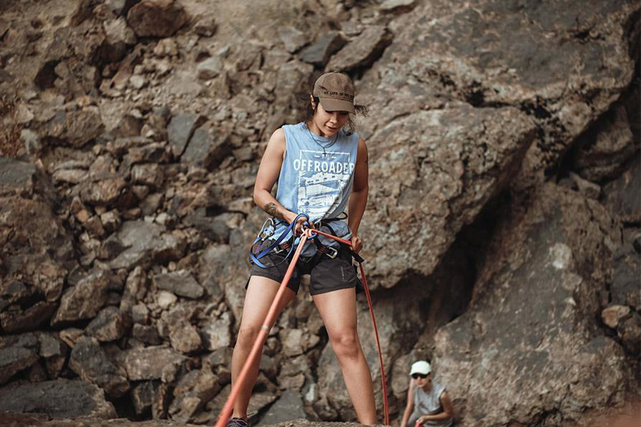 Woman hiking in a light-blue tank top and black shorts
