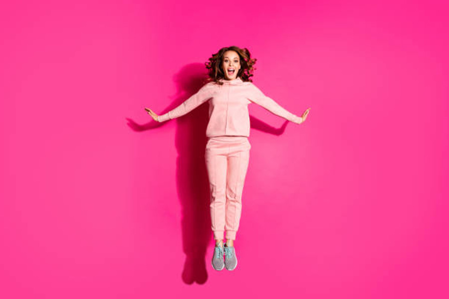 Woman jumping in pale-pink matching sweatpant suit