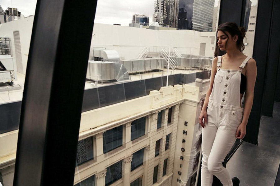 Woman standing on a balcony in a white overall