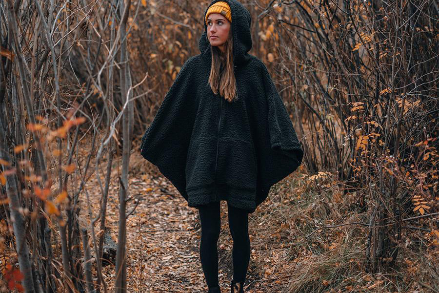 Woman wearing a black hoodie poncho in the woods