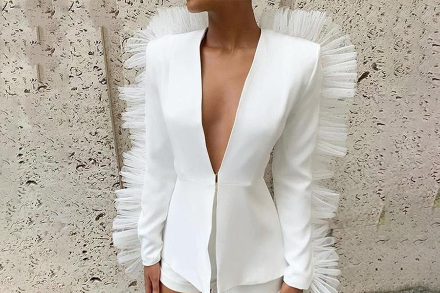 A woman wearing a white jacket with ruffles