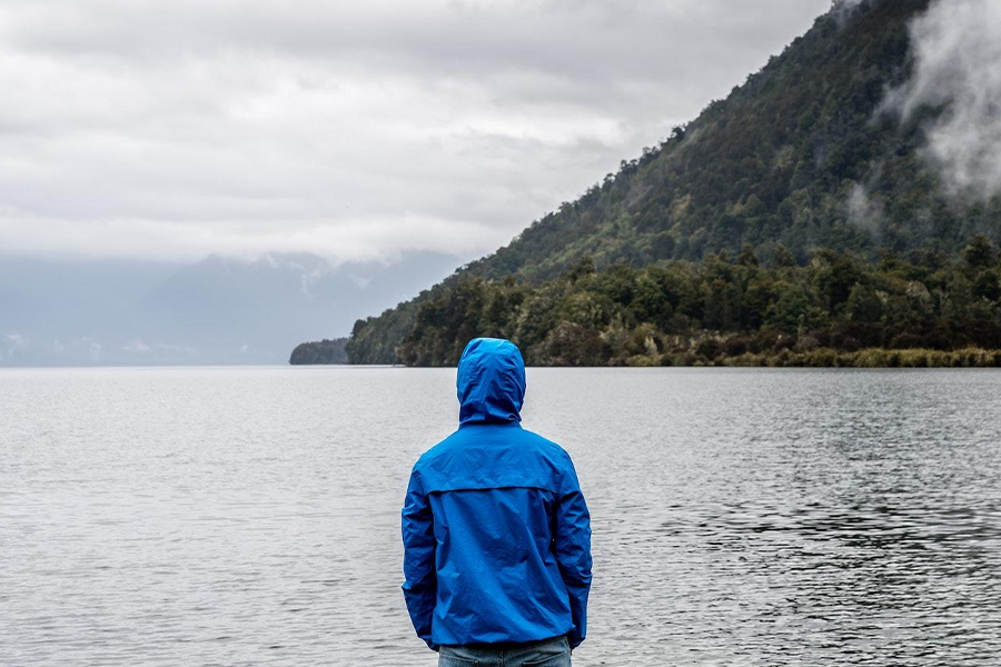 A man in a hoodie looking out into the sea