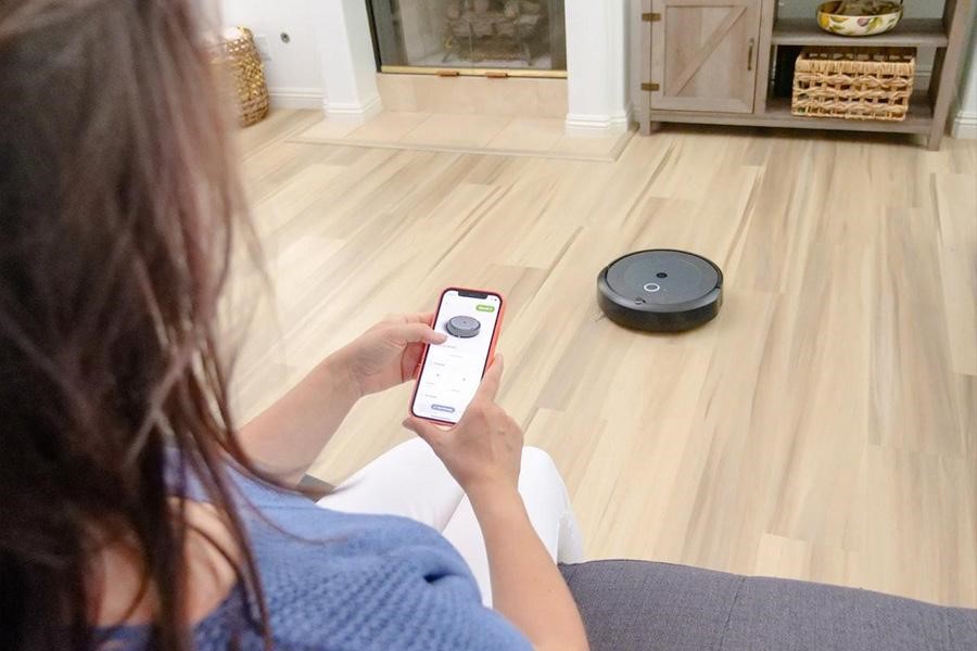 A woman operating a robot vacuum cleaner