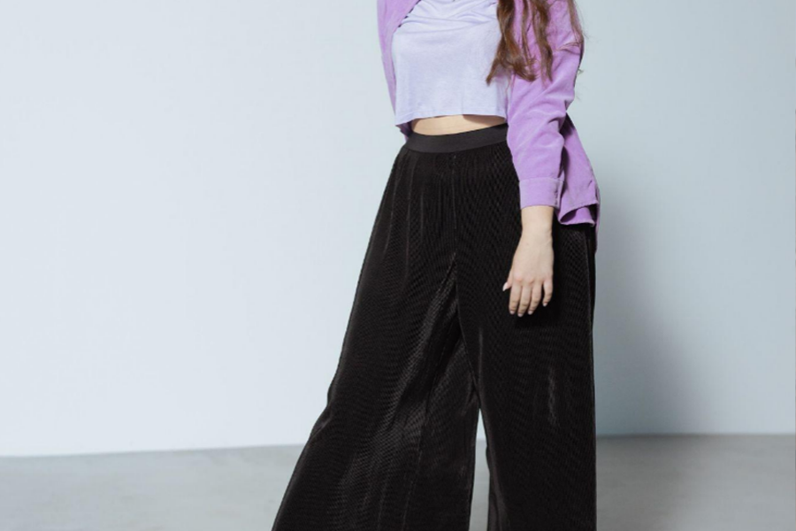 A woman wearing black pants and a purple top