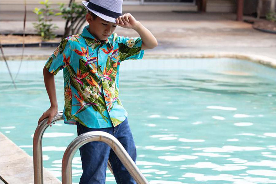 Boy in a resort shirt standing beside a pool