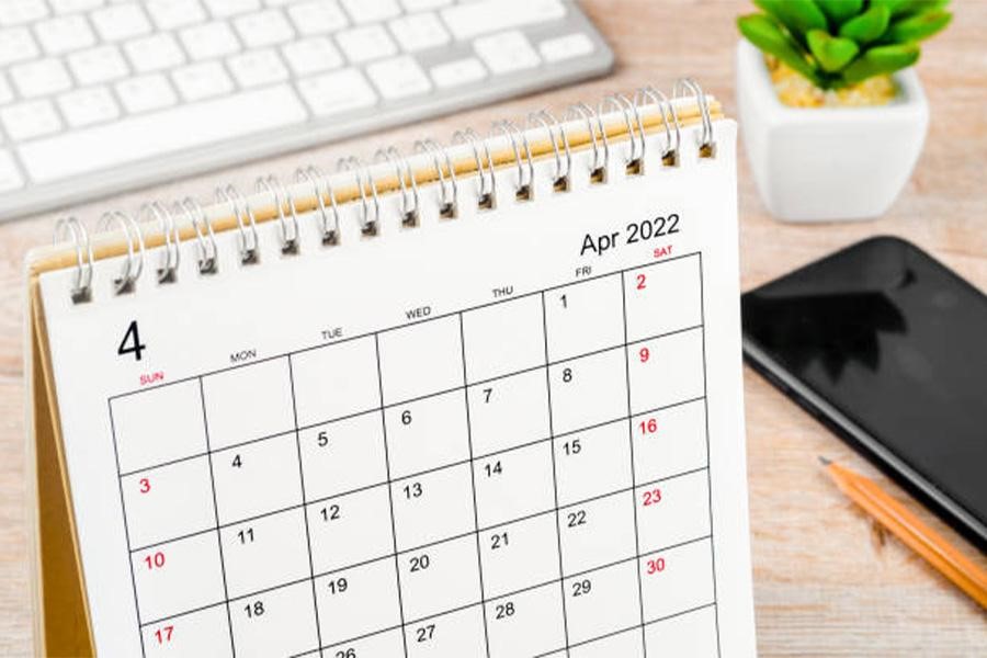 Desktop calendar opened to April next to laptop and smartphone