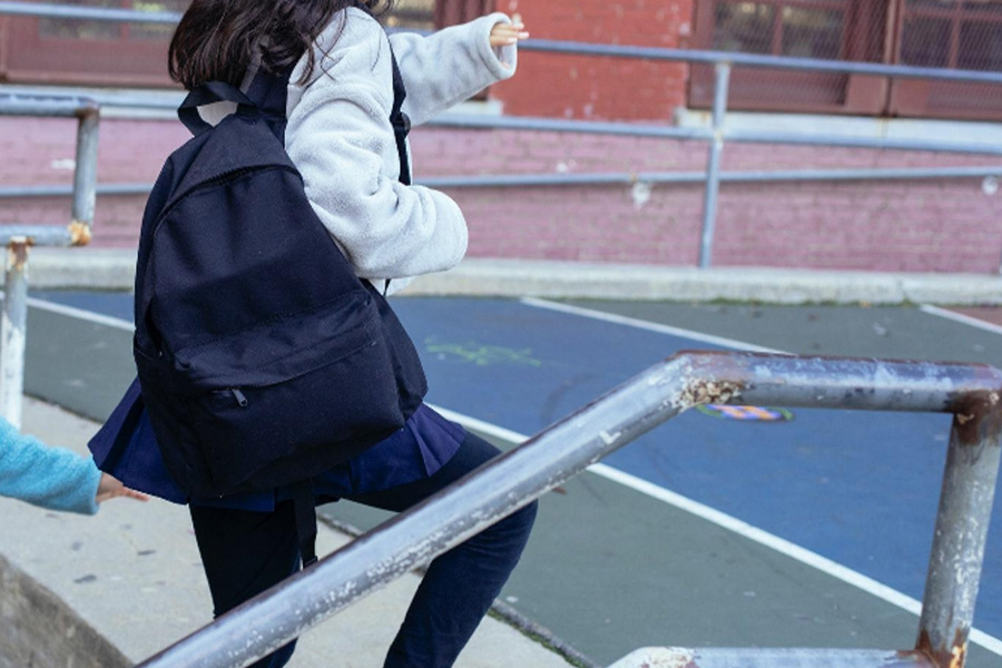 Girl climbing stairs wearing a backpack