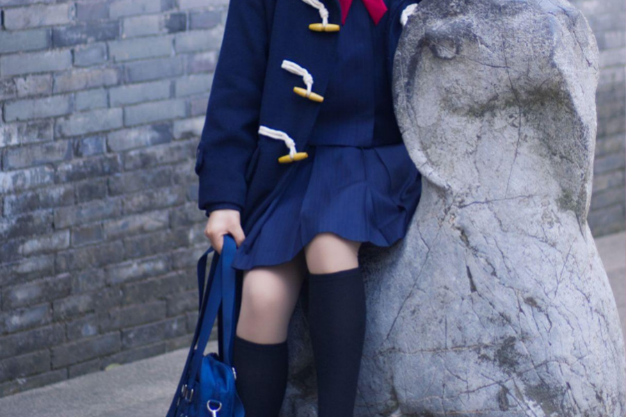 Girl wearing a blue uniform sitting on a stone