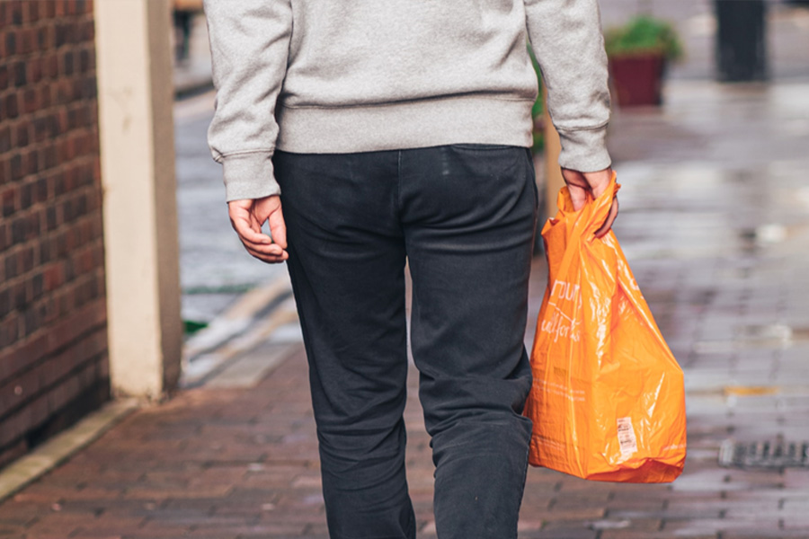 Man carrying orange plastic die cut retail bag