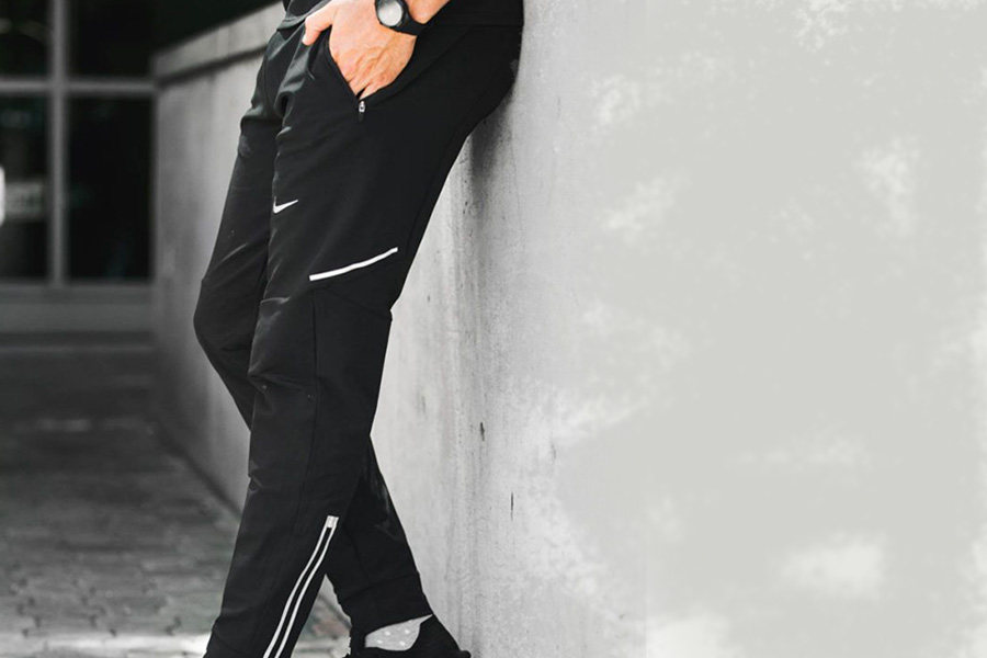 Man posing near a wall with black club trousers