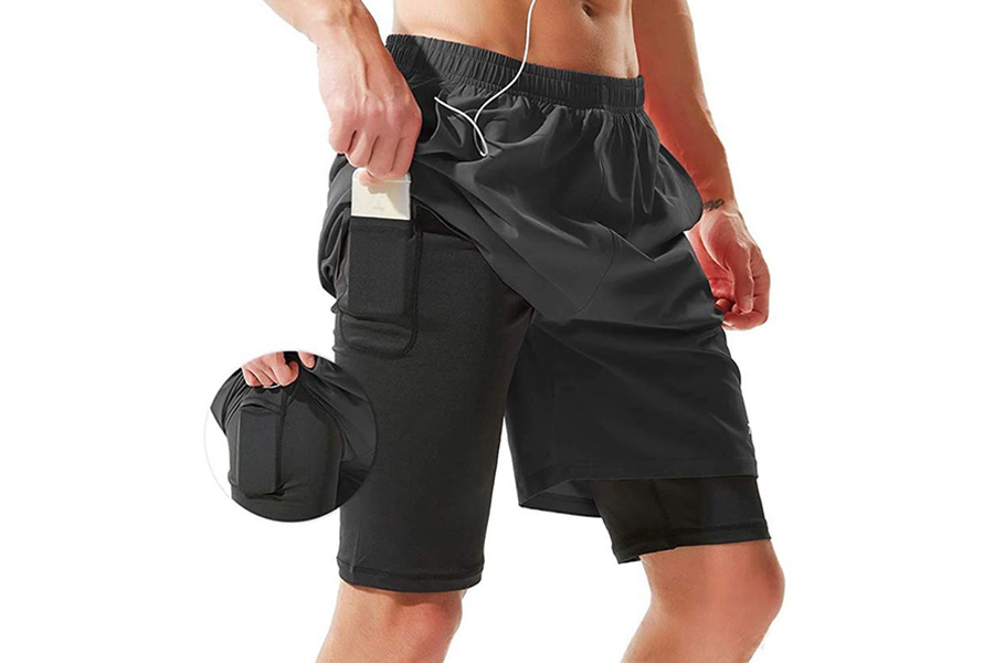 Man storing phone in black layered shorts