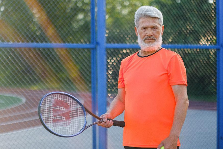 Man wearing an orange tech T-shirt with tennis racket