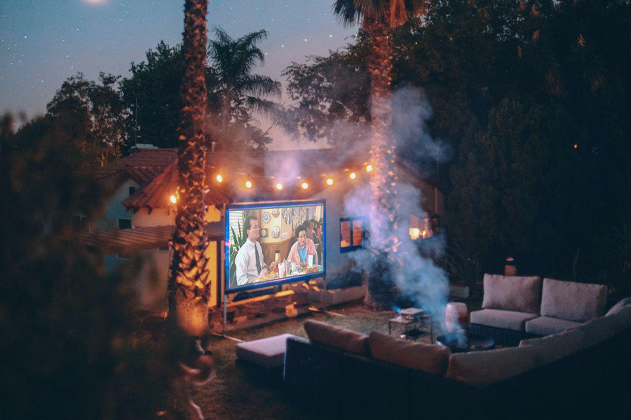 Movie being projected onto a screen in a backyard