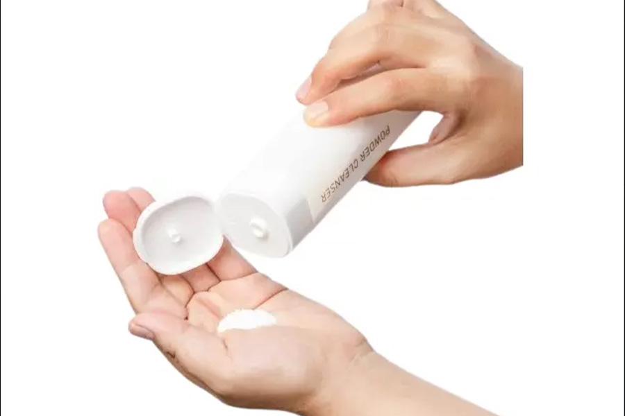 Person squeezing powder cleanser from a tube