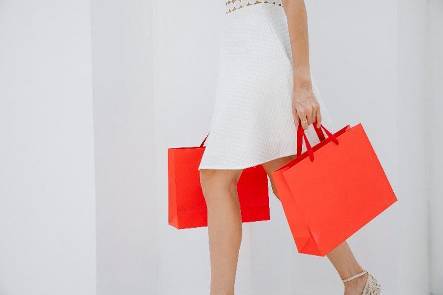 Woman carrying orange laminated paper shopping bags