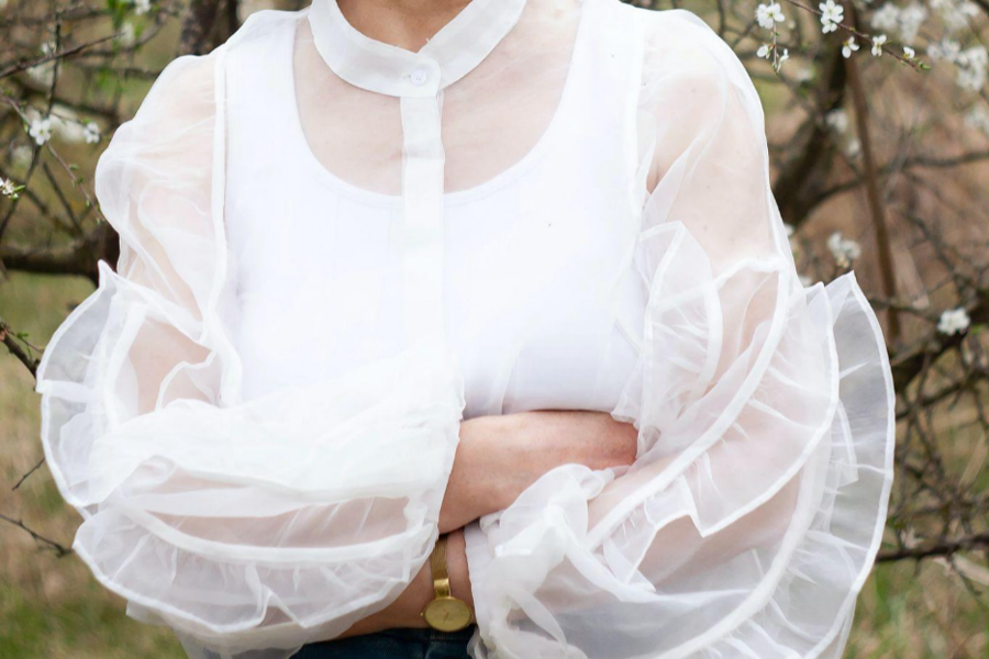 A woman wearing a transparent white top with ruffles