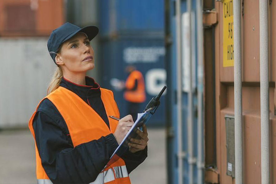 woman with clipboard checking a shipping container