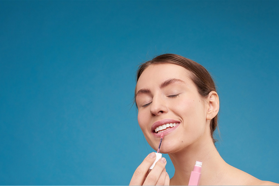 A female applying pink lip plump