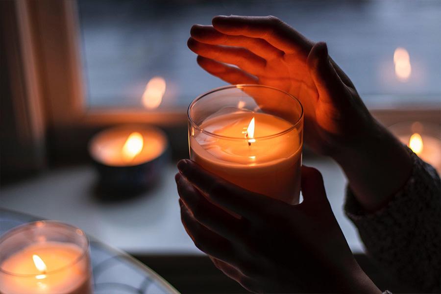 A hand hovers over a lit candle