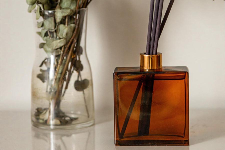 A stylish reed diffuser sits next to a decorative vase
