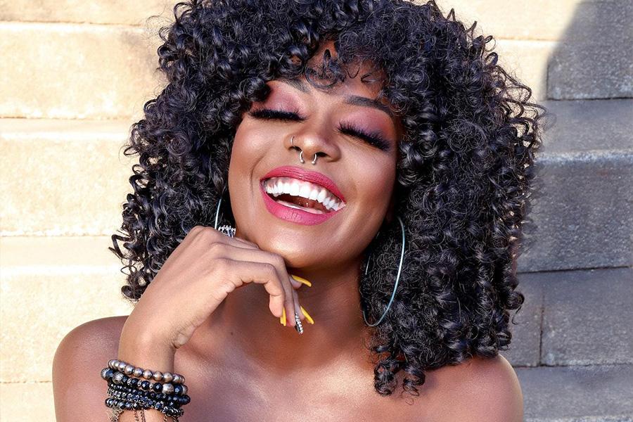 Black woman laughing sitting on stairs wearing tasteful makeup