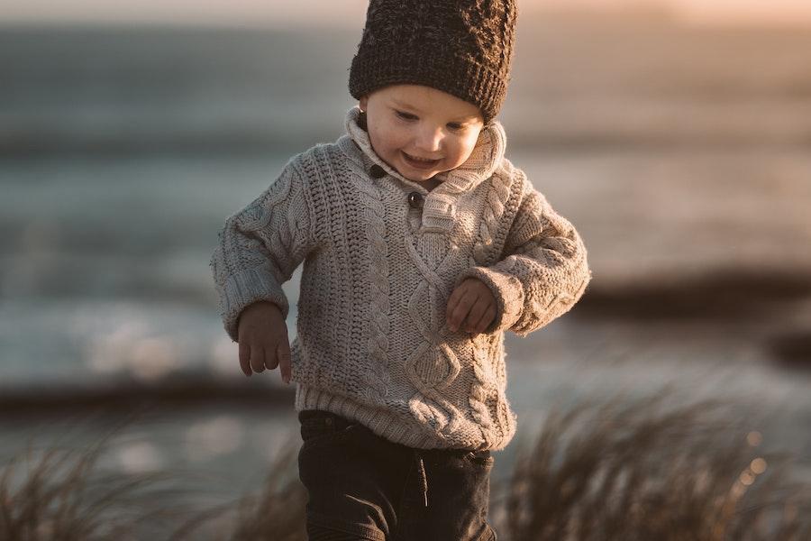 Cute child smiling with a light brown knitted sweater