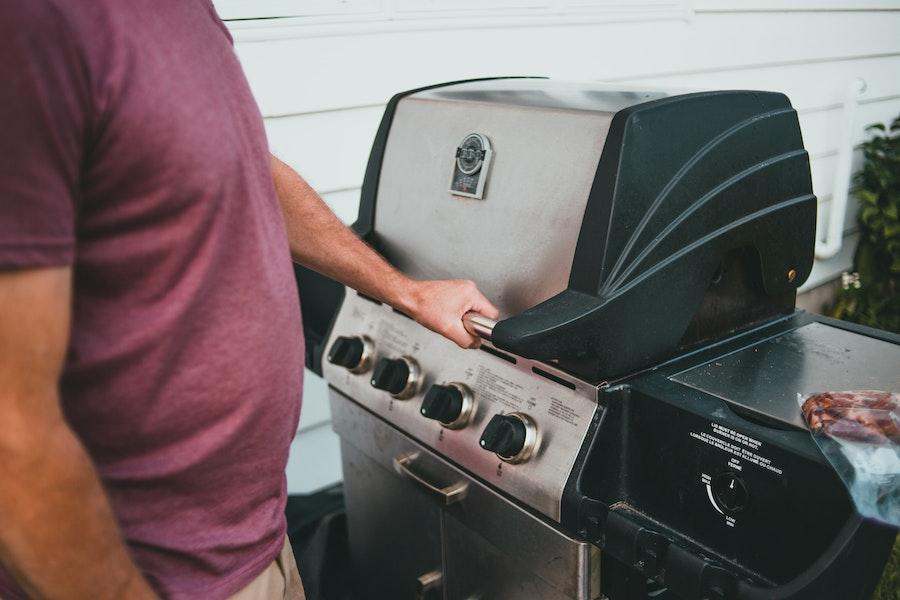 Man holding the handle of a smoker grill