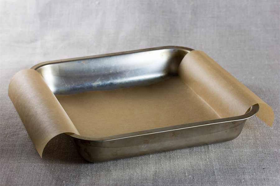 A metal cake pan ready for dough on a grey surface