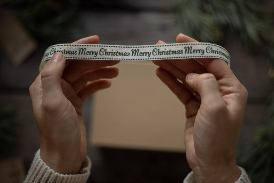 Person holding Merry Christmas gift ribbon