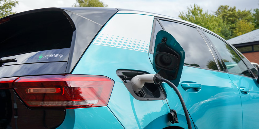 Teal blue electric vehicle plugged in at charging station