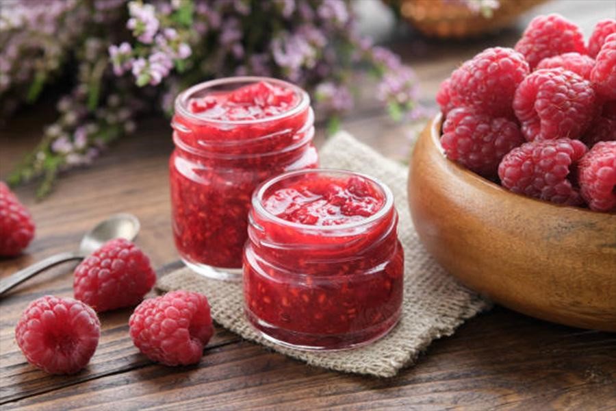 Two mini glass jars with fresh homemade raspberry jam inside