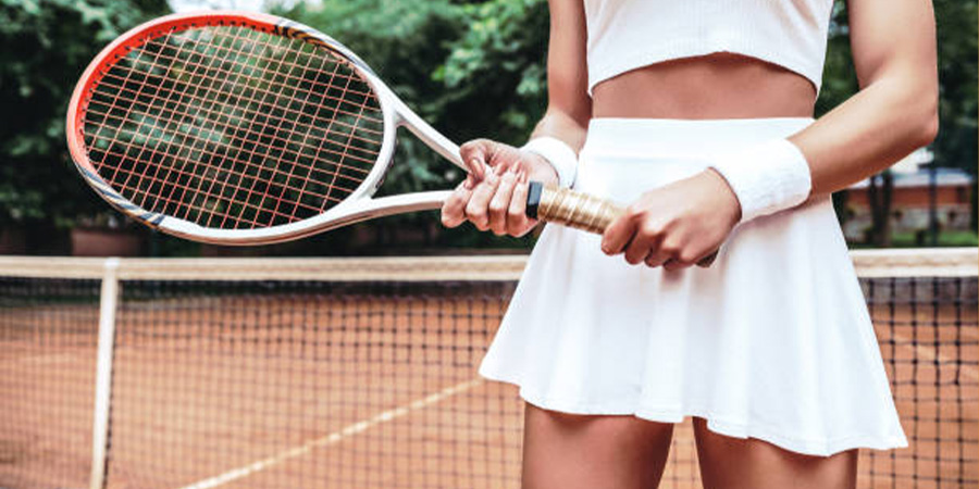 Woman in an all-white tennis outfit holding tennis racket