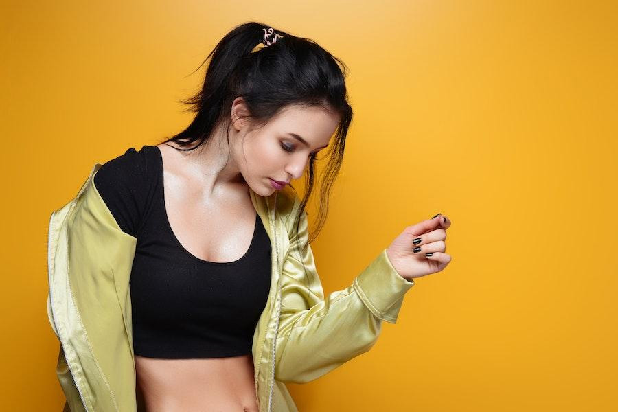 Woman posing with a black crop top and open jacket