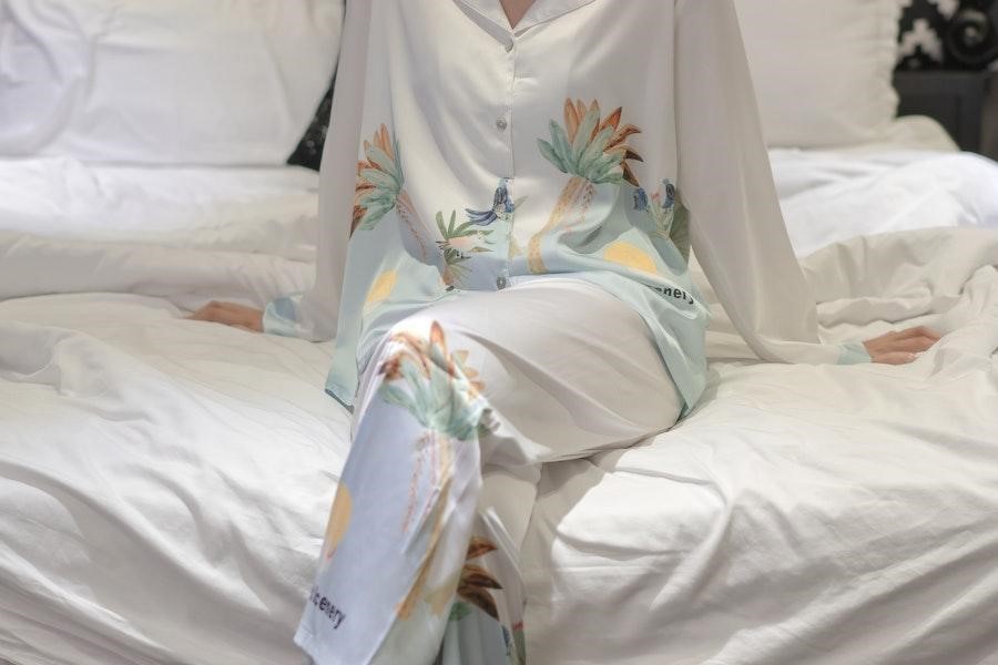 Woman sitting on a bed in a flower-print lounge set
