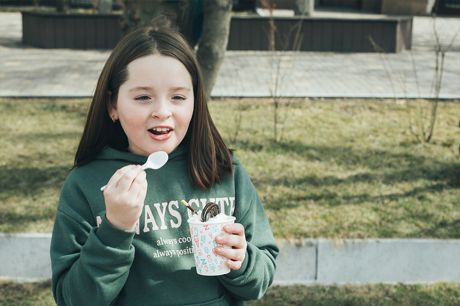 Young girl wearing a graphic sweatshirt while eating ice cream
