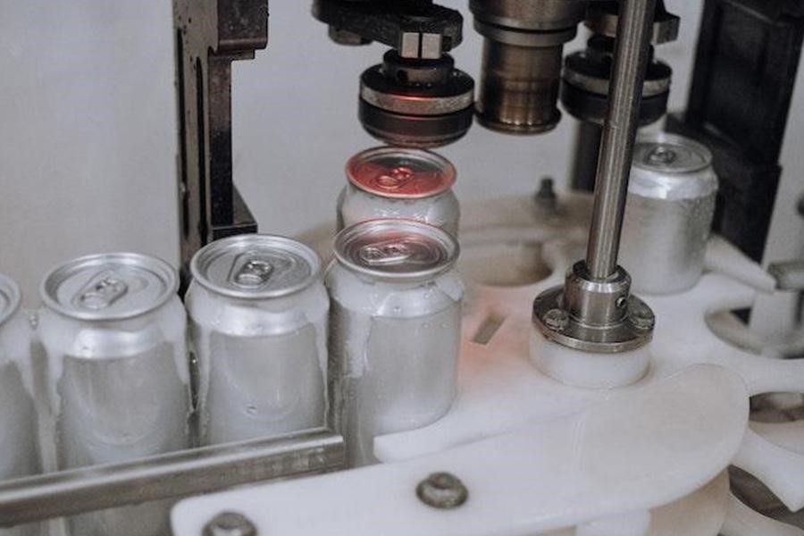 A machine sealing beer cans inside a factory